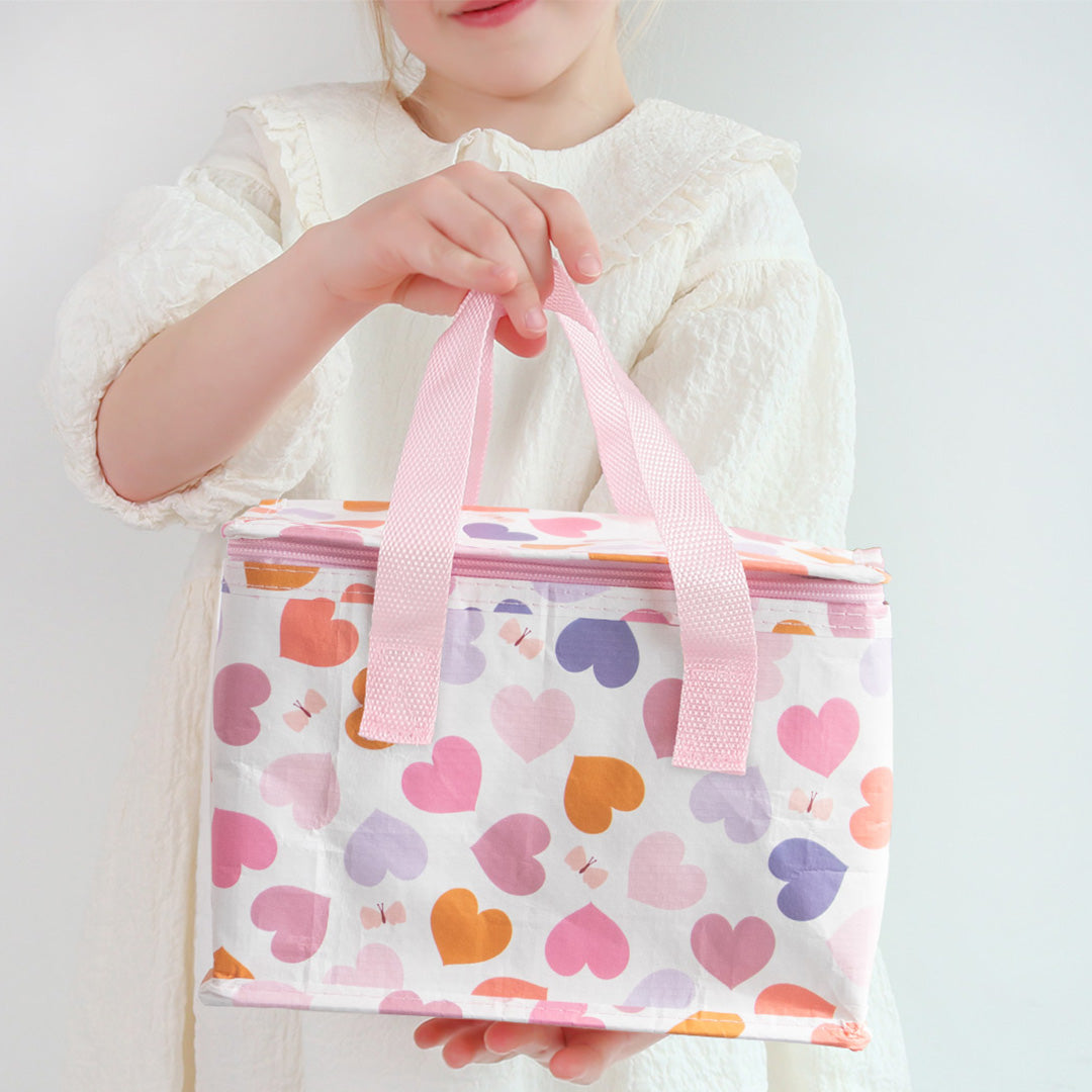 Een kind houdt de a little lovely company koeltas met hartjespatroon vast.