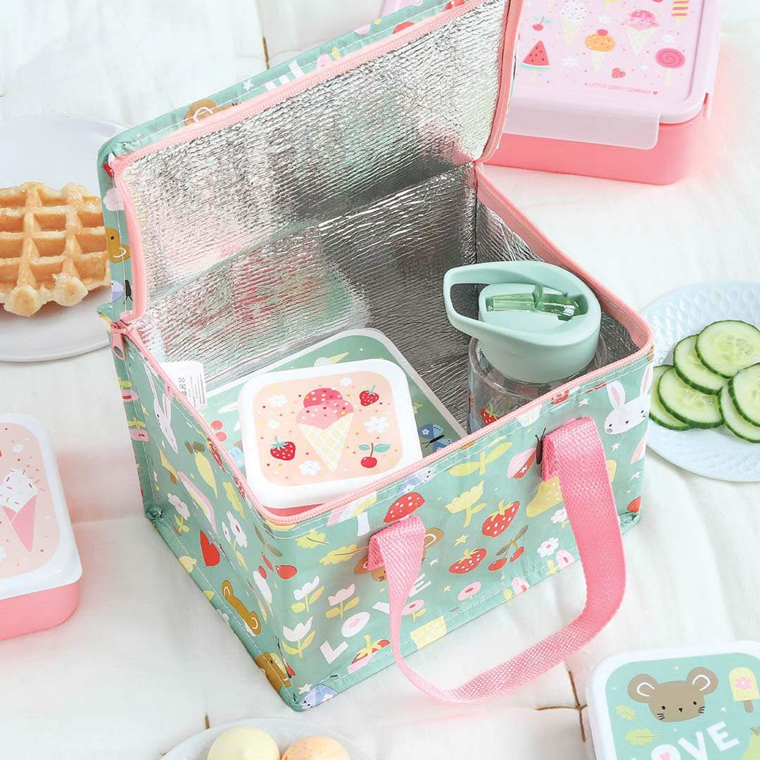 Open a little lovely company koeltas met een lunchbox en drinkfles erin, omringd door snacks.