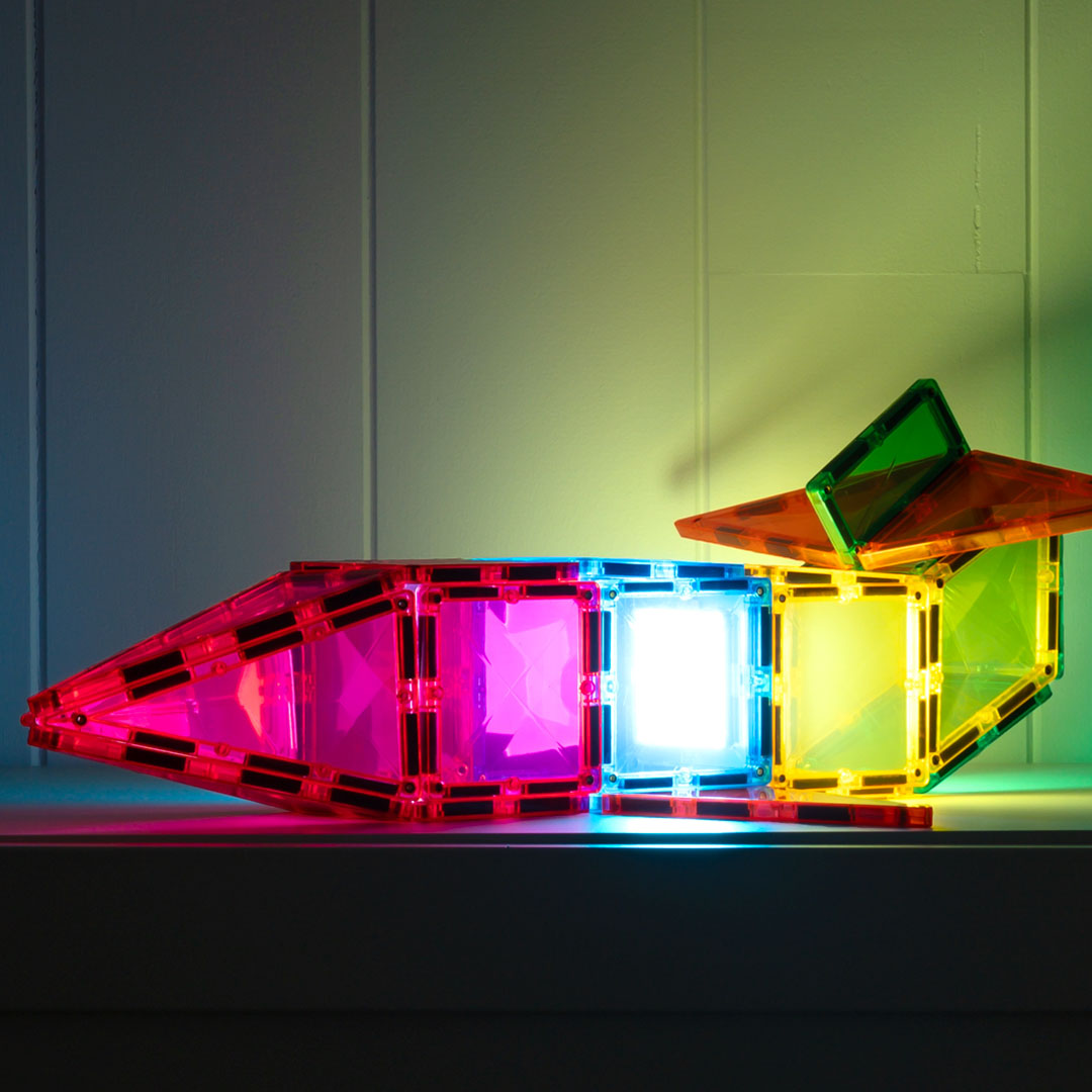 Een langwerpige constructie van Connetix magnetische tegels, waarvan de middelste tegels licht geven in verschillende kleuren.