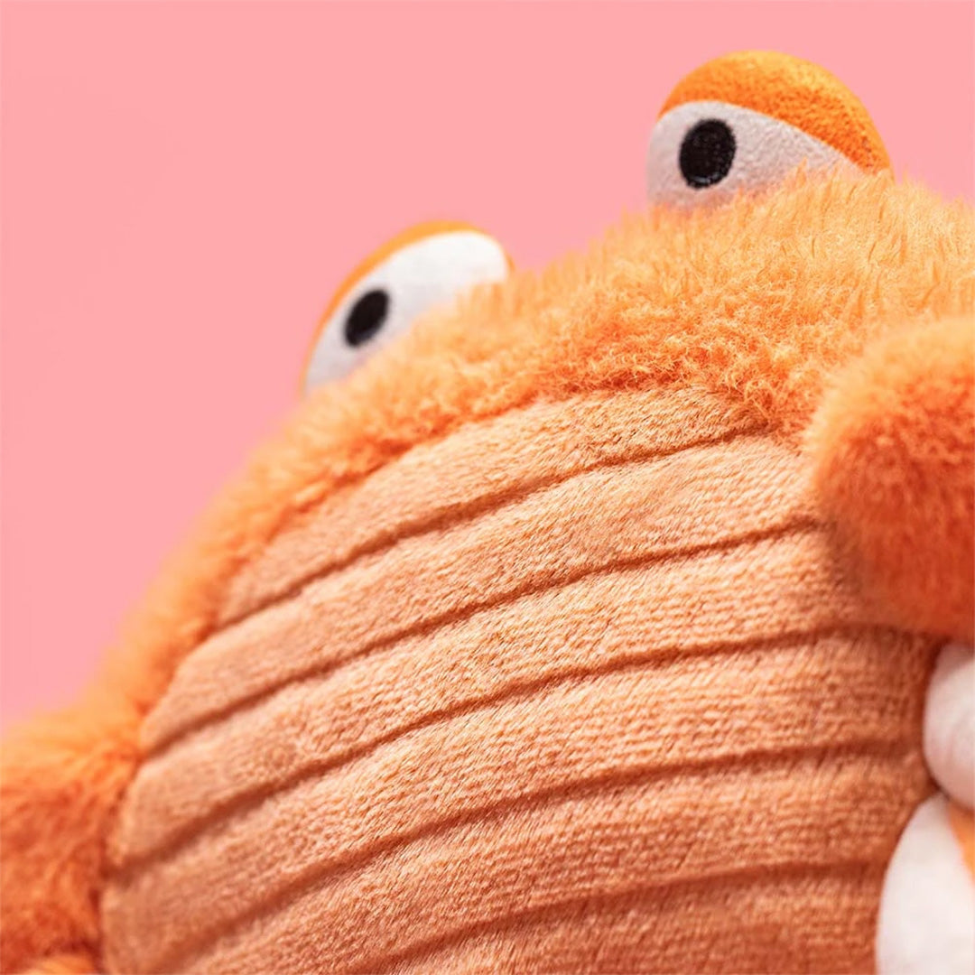 Detailopname van de oranje pluchen krab knuffel met textuur en ogen.