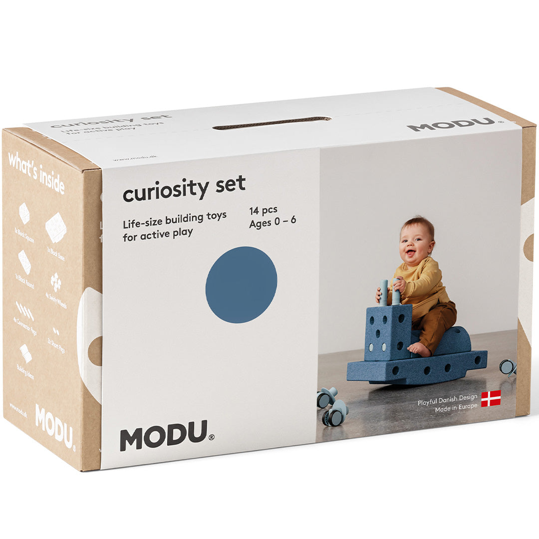 De voorkant van de modu Curiosity Set verpakking met een afbeelding van een baby op een bouwsel.