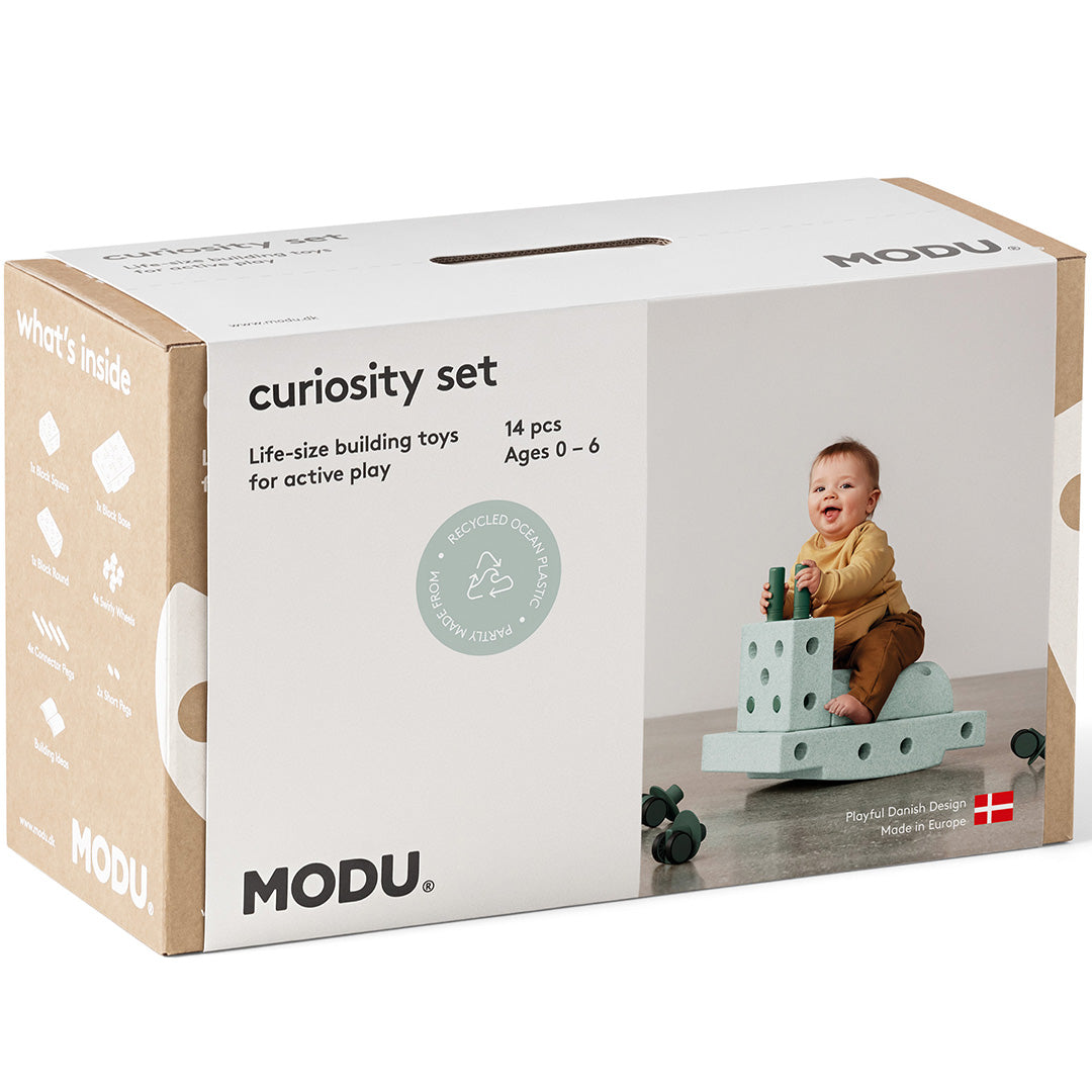 De verpakking van de Modu Curiosity Set met een afbeelding van een baby die speelt met de bouwblokken.