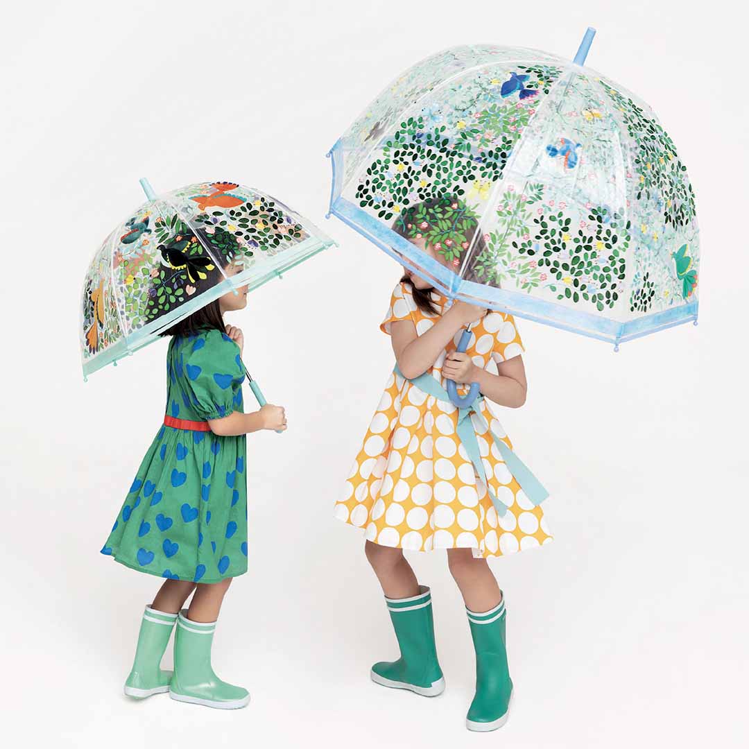 Twee kinderen met Djeco kinderparaplu's met bloemen- en vogelpatronen.
