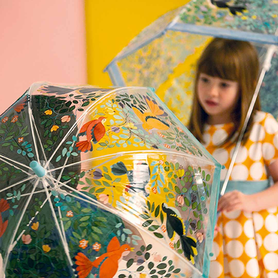 Detail van een Djeco kinderparaplu met een kleurrijk patroon van bloemen en vogels.