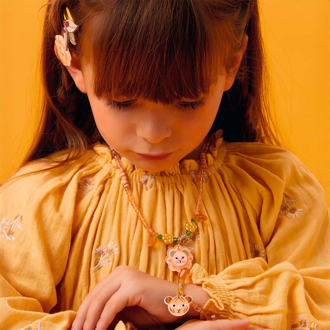 Een kind draagt de Djeco kinderketting met leeuwenkop hanger en een bijpassende armband.