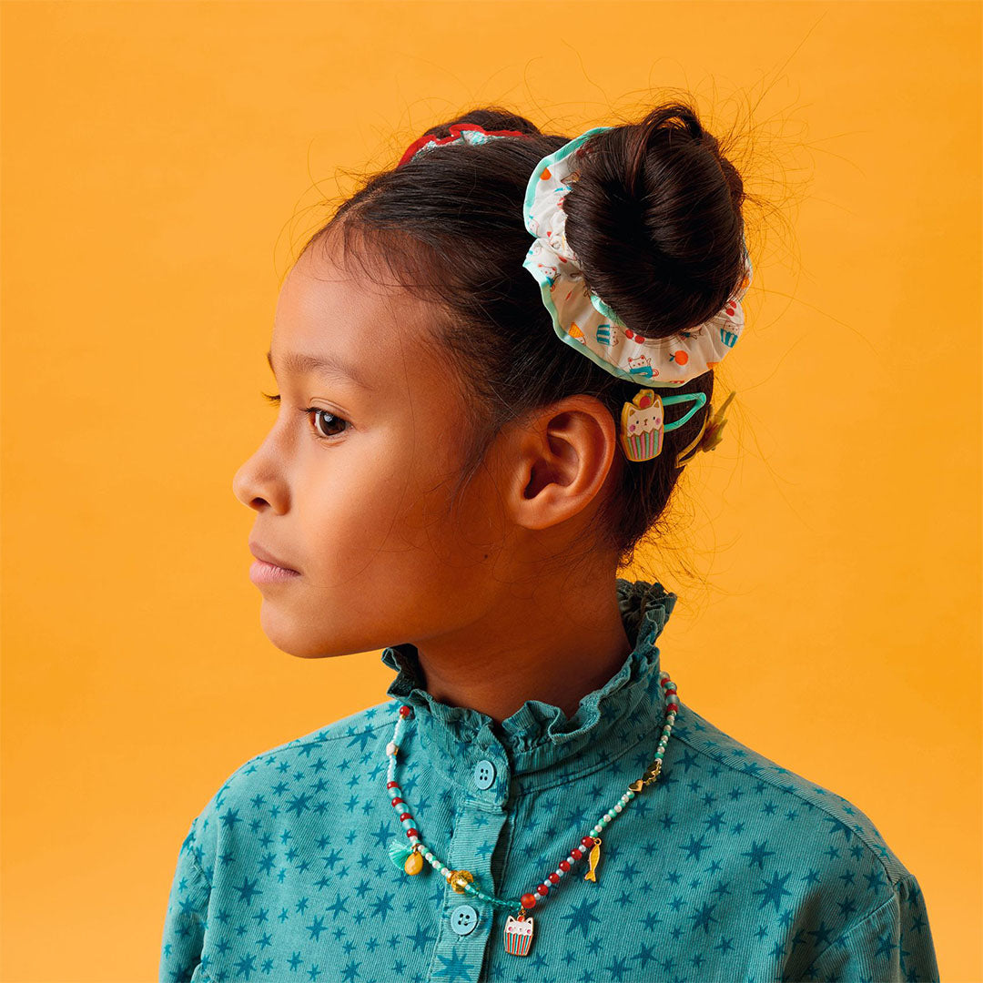 Meisje met een Djeco scrunchie met ijsjesprint in een knot, van opzij gefotografeerd.