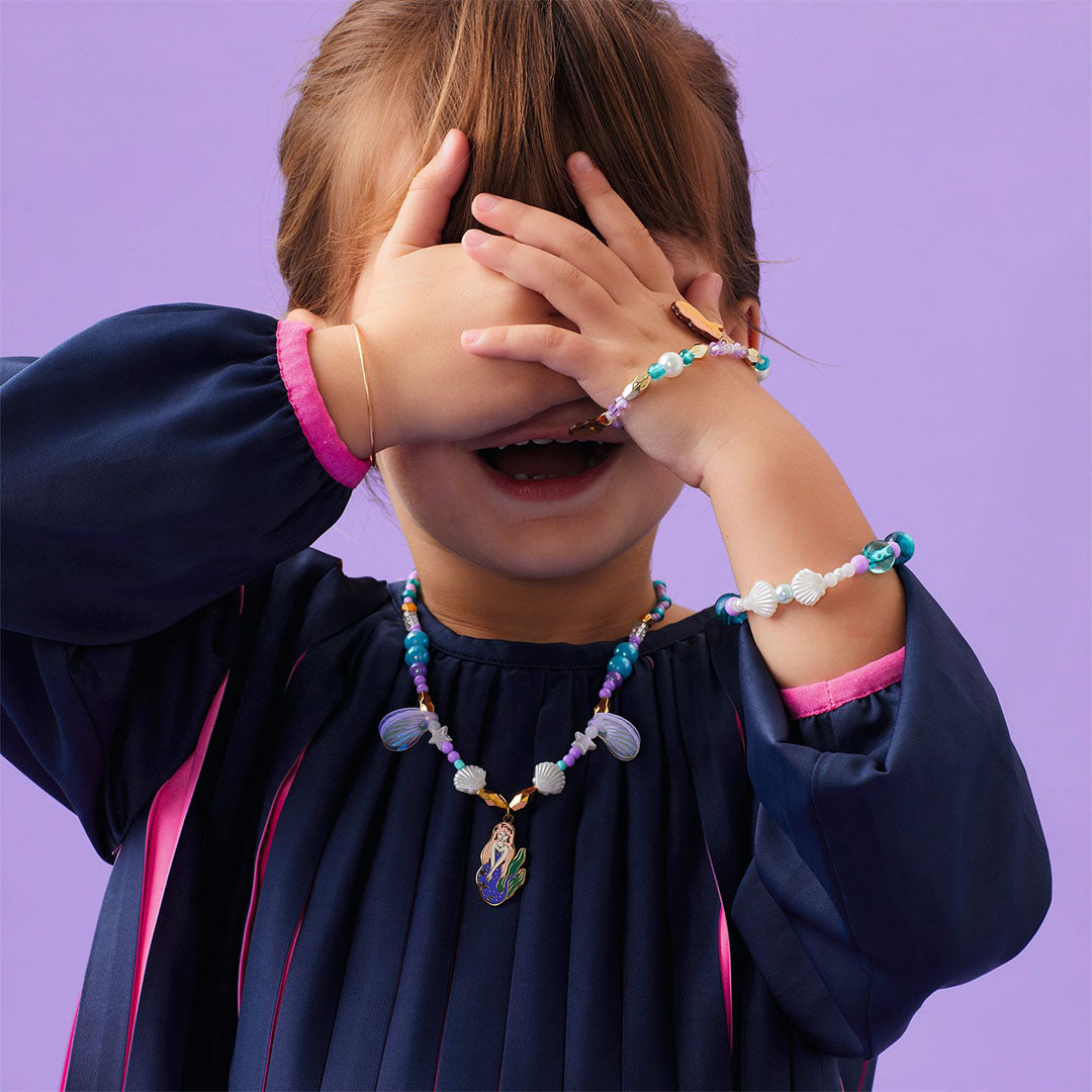Een kind draagt de Djeco kinderketting met zeemeermin hanger en een bijpassende kralenarmband.