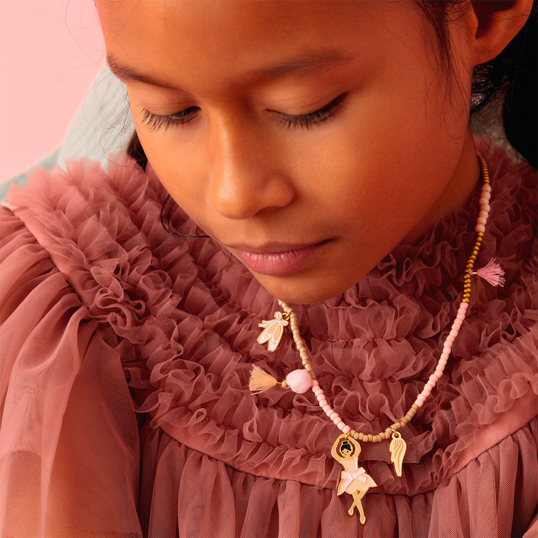 Een kind draagt de Djeco kinderketting met ballerina-bedeltjes om haar nek.