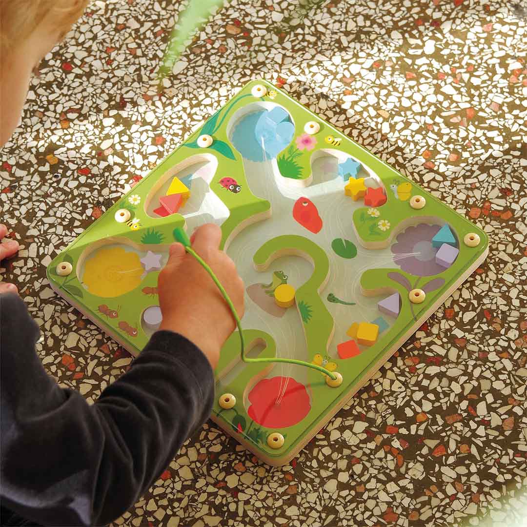 Een kind speelt met het Djeco magnetisch vormenspel FrogyMaze, waarbij een vorm met de magnetische pen wordt verplaatst.
