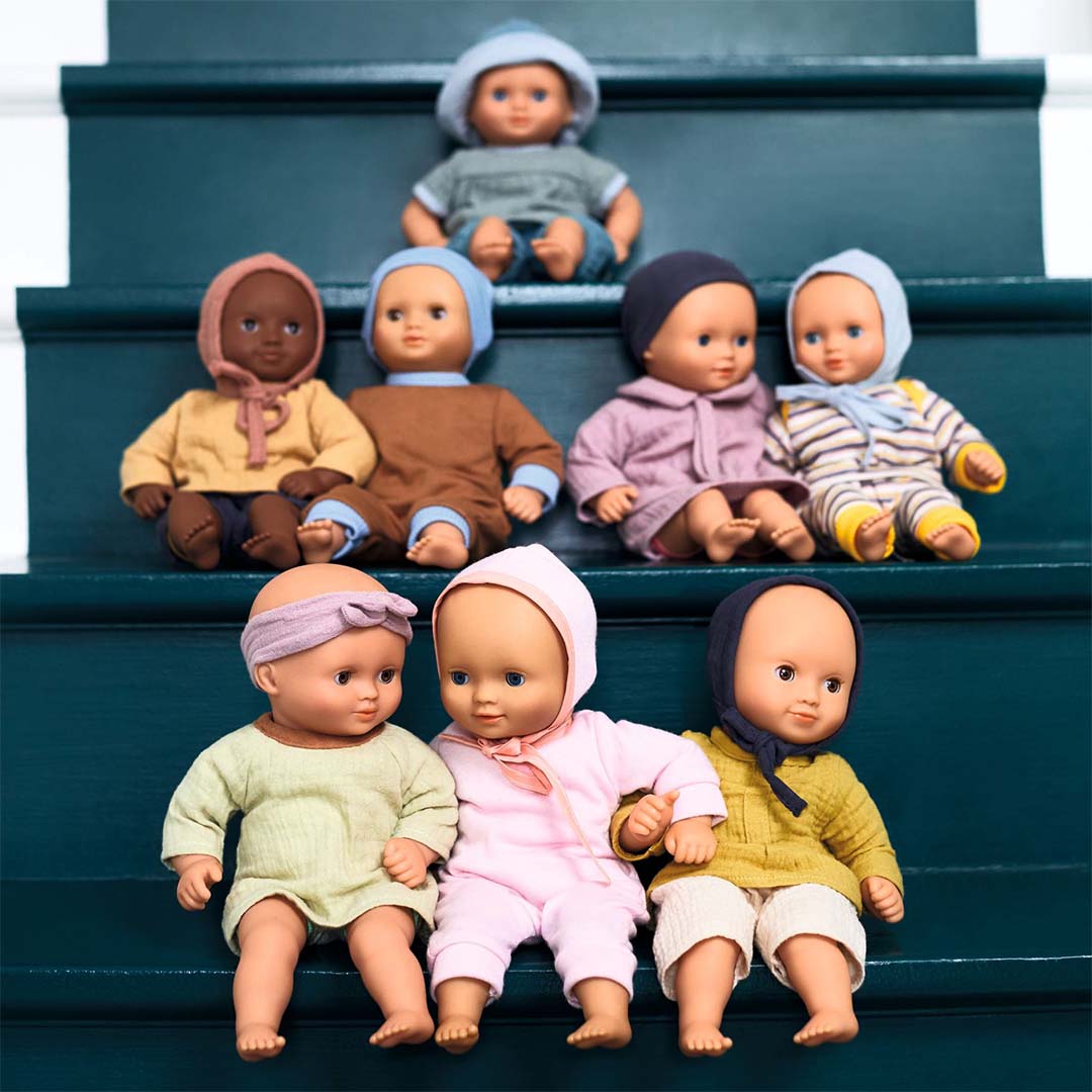 Collectie van Djeco babypoppen Pomea in verschillende outfits zittend op een trap.