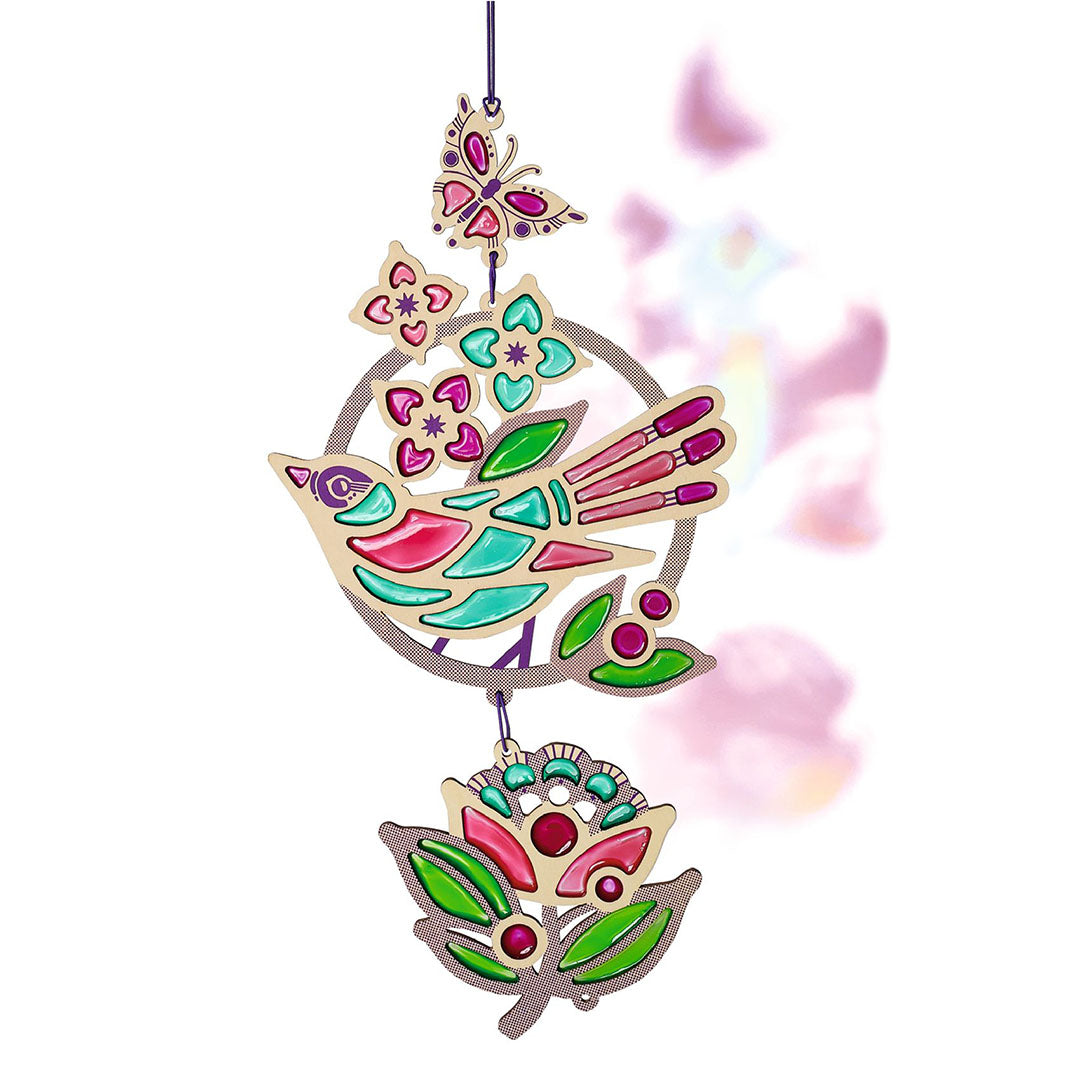 Een afgewerkte glas-in-lood zonnevanger met een vogel, bloem en vlinder in roze, groen en blauw.