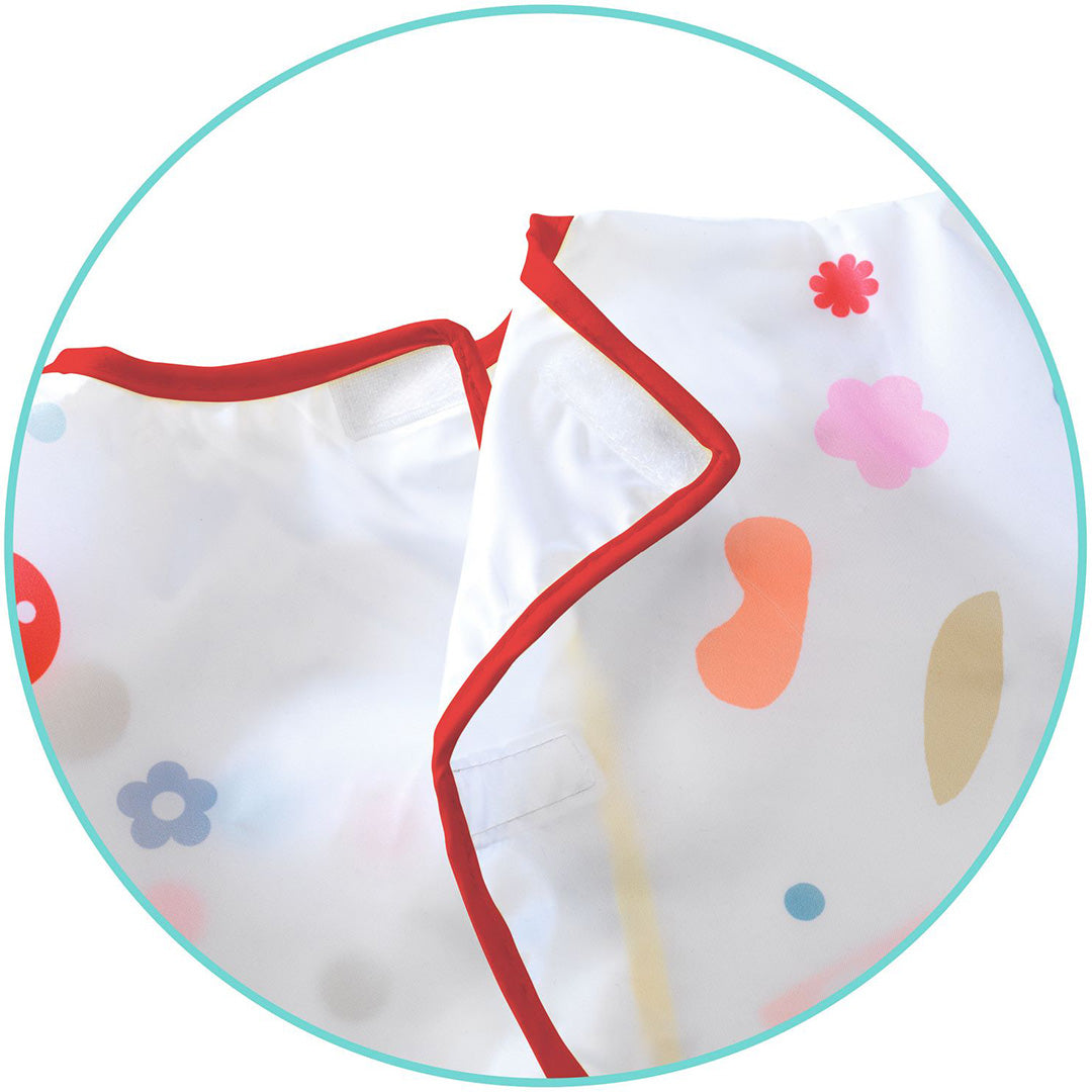 Detailfoto van de achterkant van het Djeco kliederschort met rode bies en klittenbandsluiting.