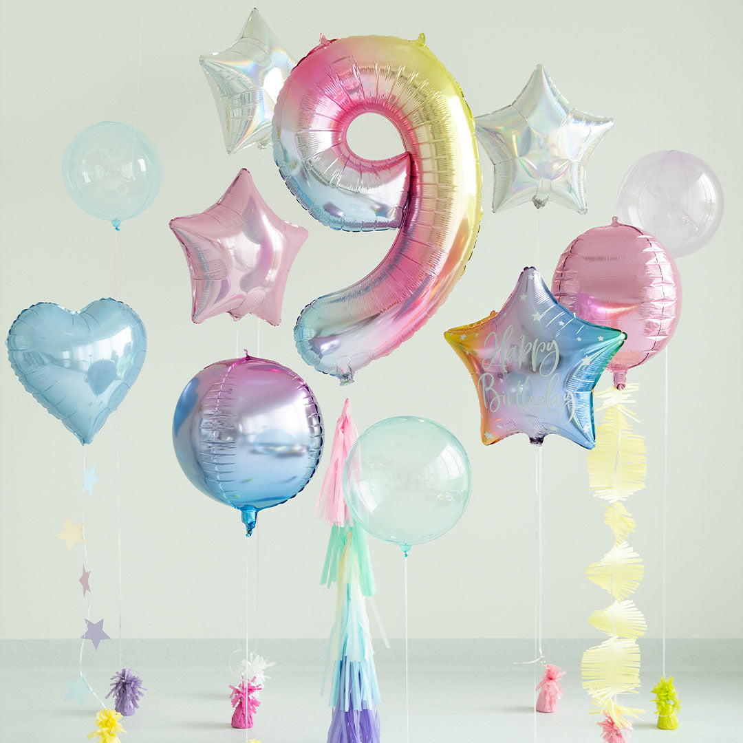 Een collectie van diverse feestballonnen, waaronder de pastel regenboog cijferballon 9, hartvormige en stervormige ballonnen.