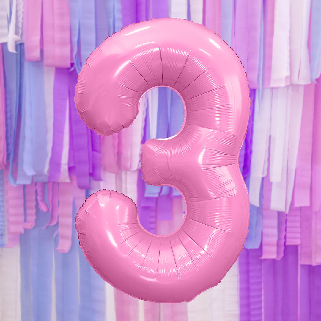 Partydeco roze cijferballon 3 zwevend voor een achtergrond van roze, paarse en witte slingers.