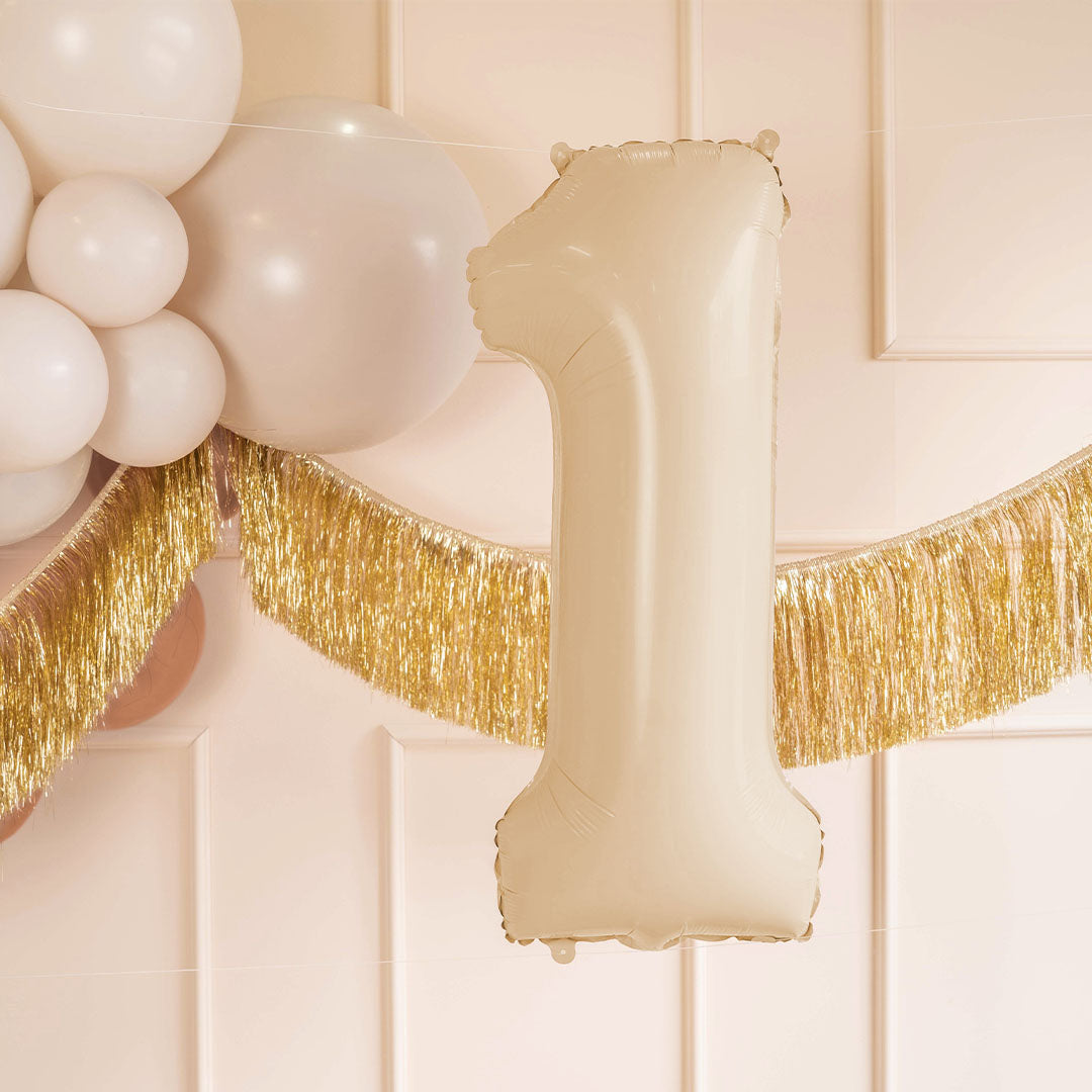 Partydeco beige cijferballon 1 als feestdecoratie met witte ballonnen en een gouden slinger.