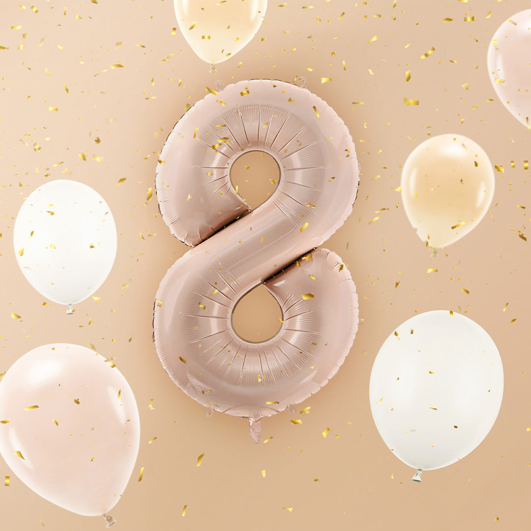 Partydeco roségouden cijferballon 8 zwevend tussen kleinere ballonnen en gouden confetti.