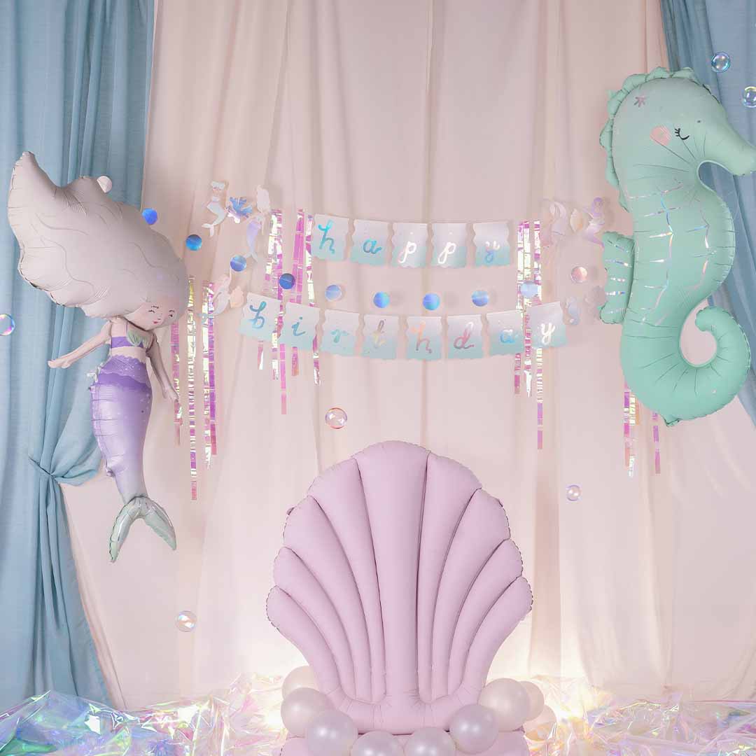 partydeco feestdecoratie met een zeemeermin- en zeepaardjeballon en een 'happy birthday' slinger tegen een lichte achtergrond.