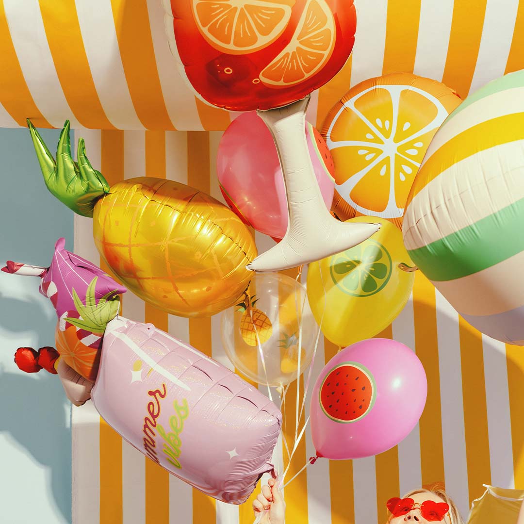 Een collectie van diverse zomerse folieballonnen, waaronder een roze cocktailglas, ananas en fruit.