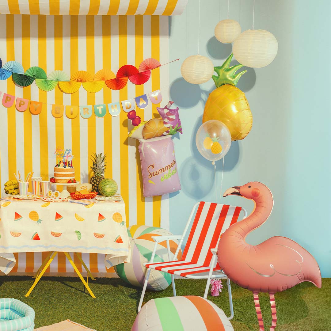 Roze flamingo folieballon als onderdeel van een zomerse verjaardagsdecoratie met een gestreepte achtergrond.