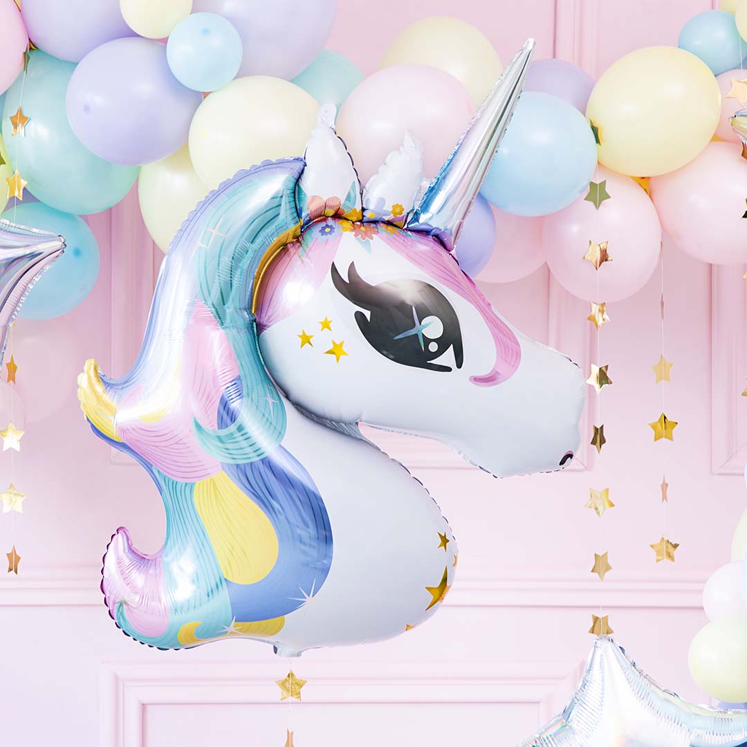 Een eenhoorn folieballon met veelkleurige manen en sterren, als onderdeel van een feestdecoratie met pastelkleurige ballonnen.