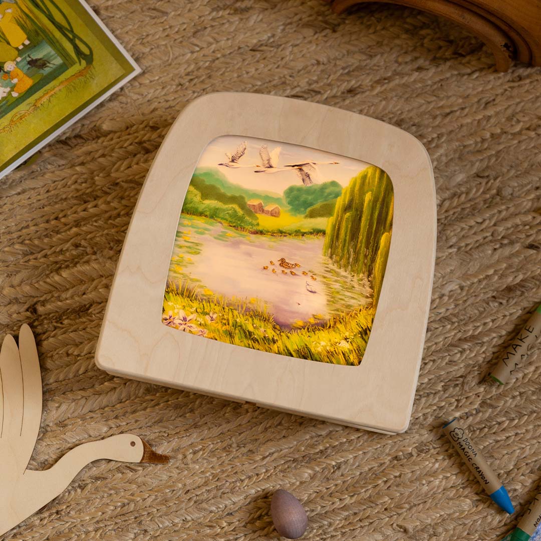 De Toverlux toverplaat 'Het lelijke eendje' verlicht in een houten toverlamp, schuin gefotografeerd met speelgoed op de achtergrond.
