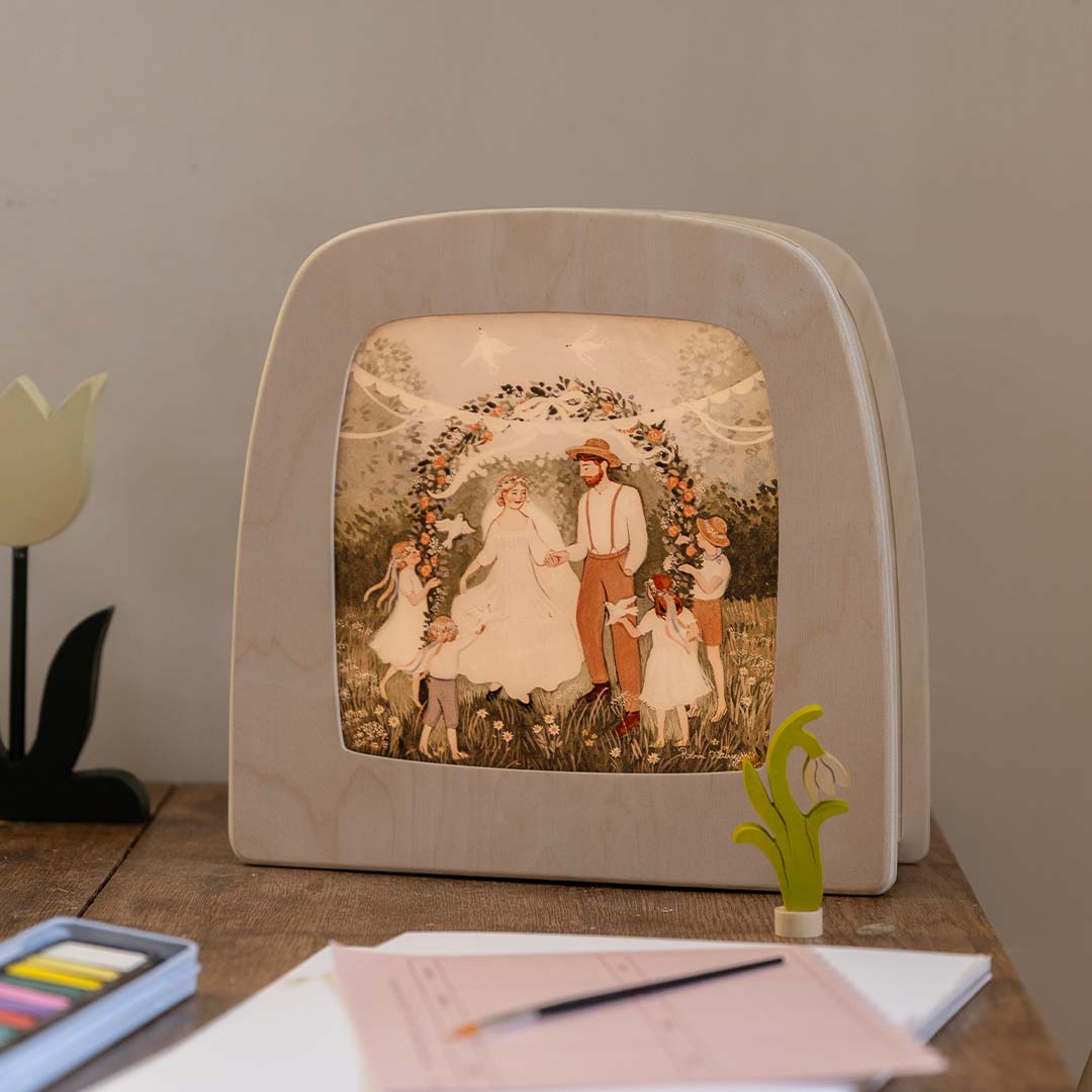 De toverlux toverplaat 'Belofte' met bruiloftsthema in een houten frame, staand op een houten tafel.