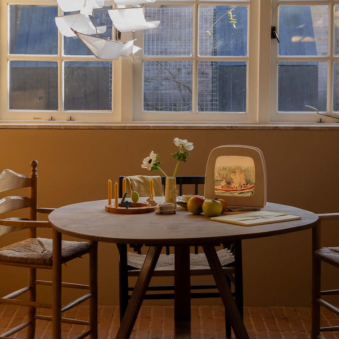 De toverlux toverlamp met de toverplaat van de kinderen in een bootje staat op een houten tafel in een kamer.