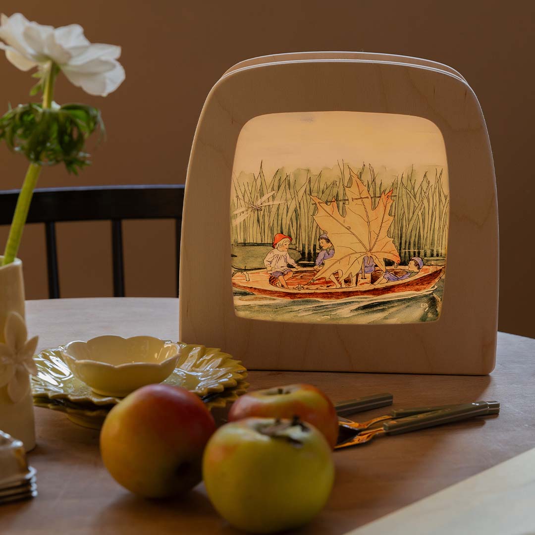 De toverlux toverlamp met de toverplaat van de kinderen in een bootje, staand op een houten tafel.