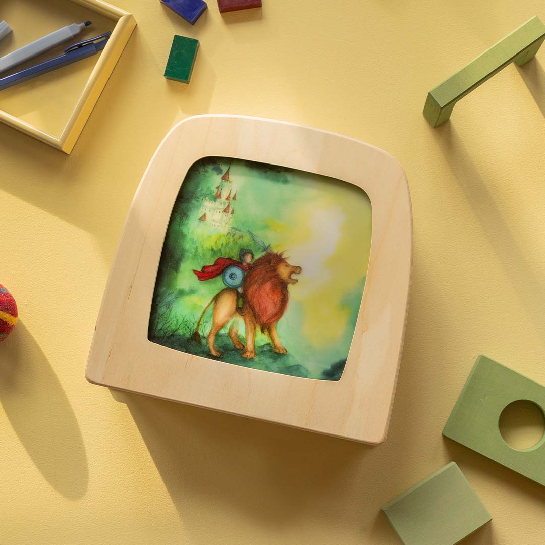 Toverluxe toverplaat met een illustratie van een ridder op een leeuw, liggend op een gele ondergrond tussen speelgoed.