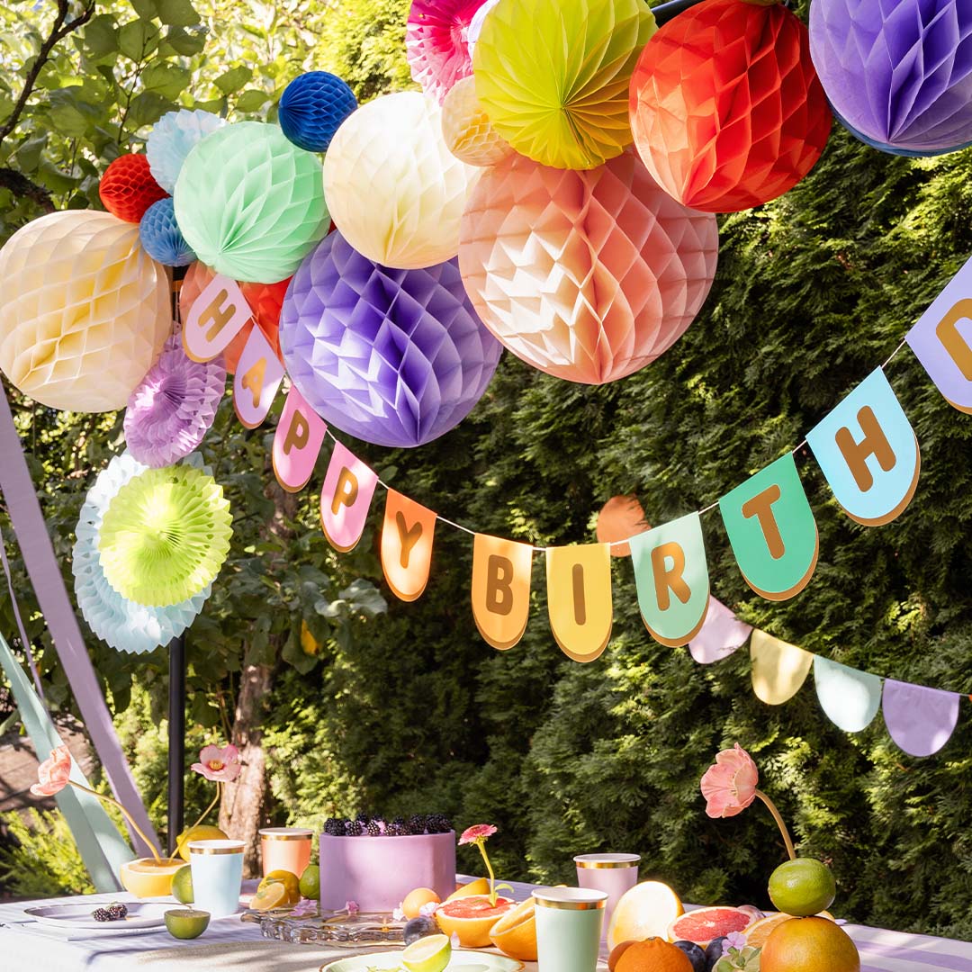 PartyDeco 'Happy Birthday' slinger hangt boven een feestelijk gedekte tafel in een tuin.