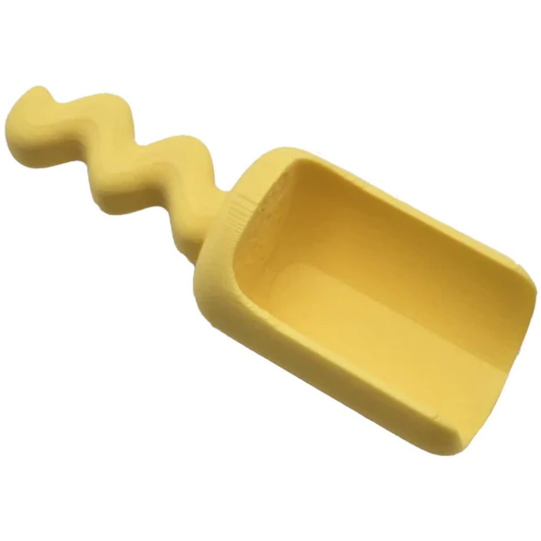 Een geel grennn zandschepje met een golvend handvat.