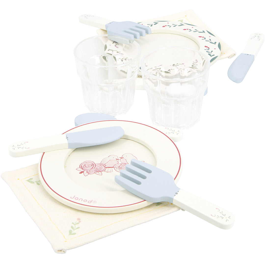 Detail van de Janod speelgoed dinerset met twee borden met rozenpatroon, bestek, glazen en gebloemde servetten.