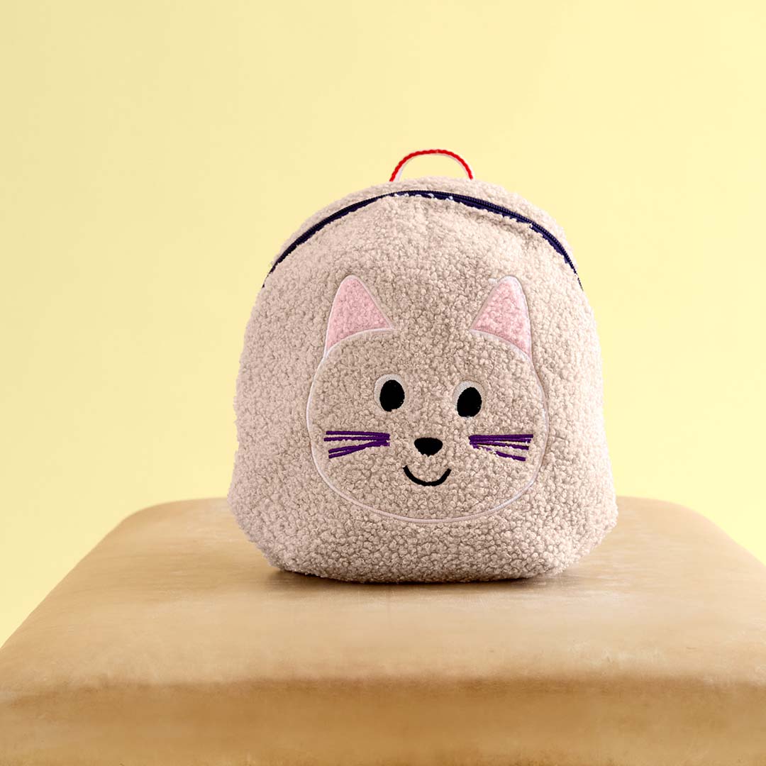 Lässig beige peuterrugzak met kattengezicht op een bruine ondergrond.