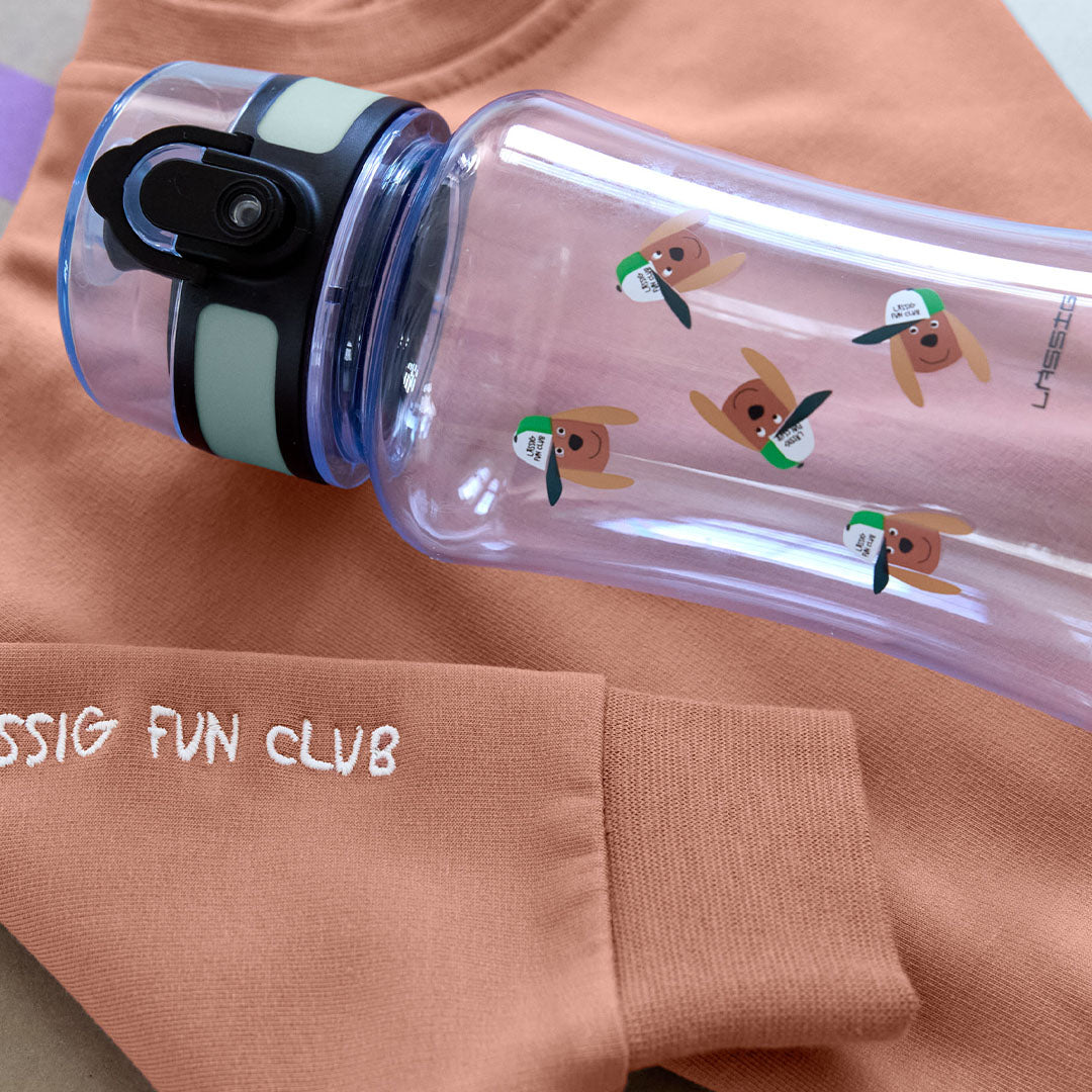 Lässig transparante kinder drinkfles met hondenpatroon liggend op een perzikkleurig kledingstuk.