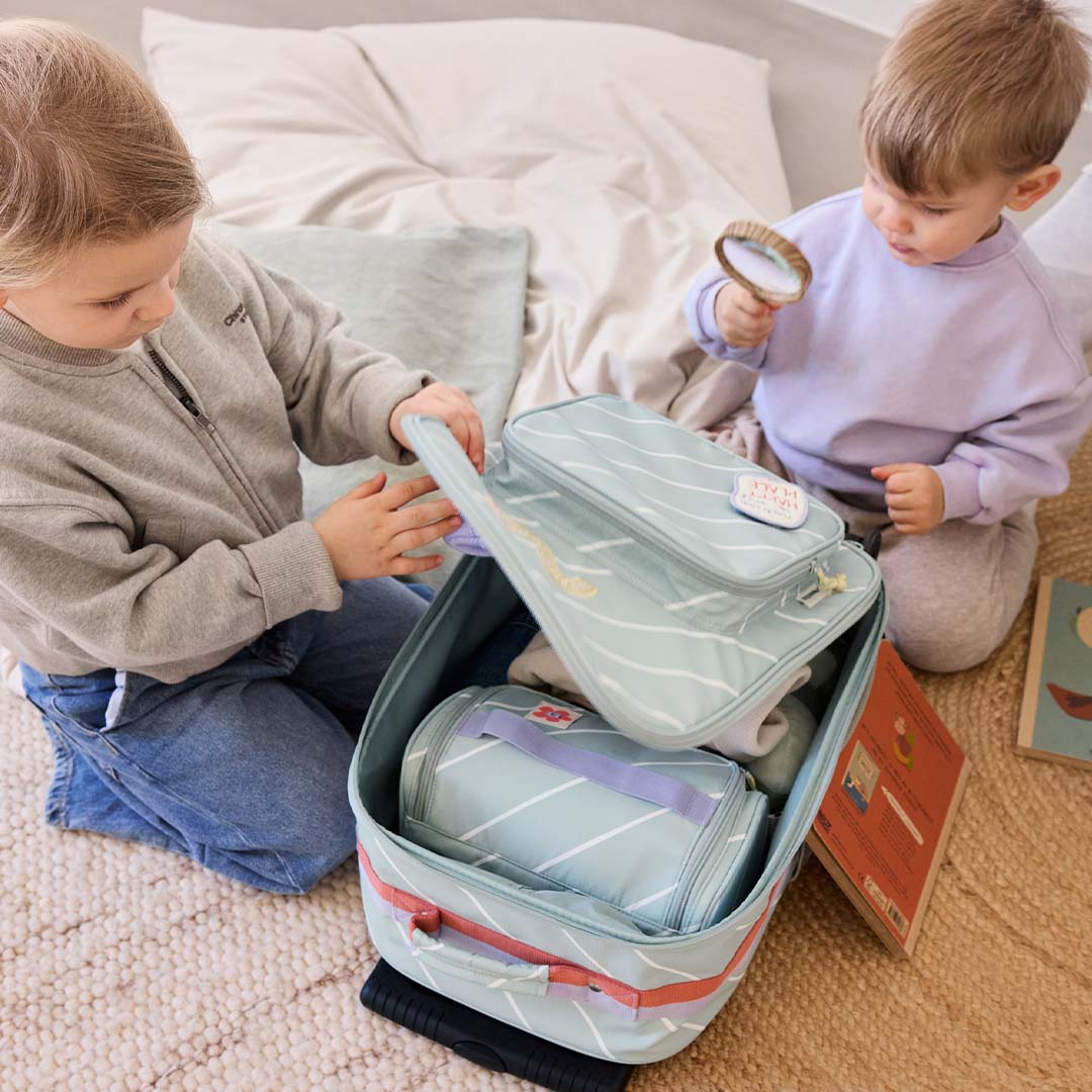 Twee kinderen spelen met de open Lässig kinderkoffer, gevuld met kleinere bijpassende tassen.