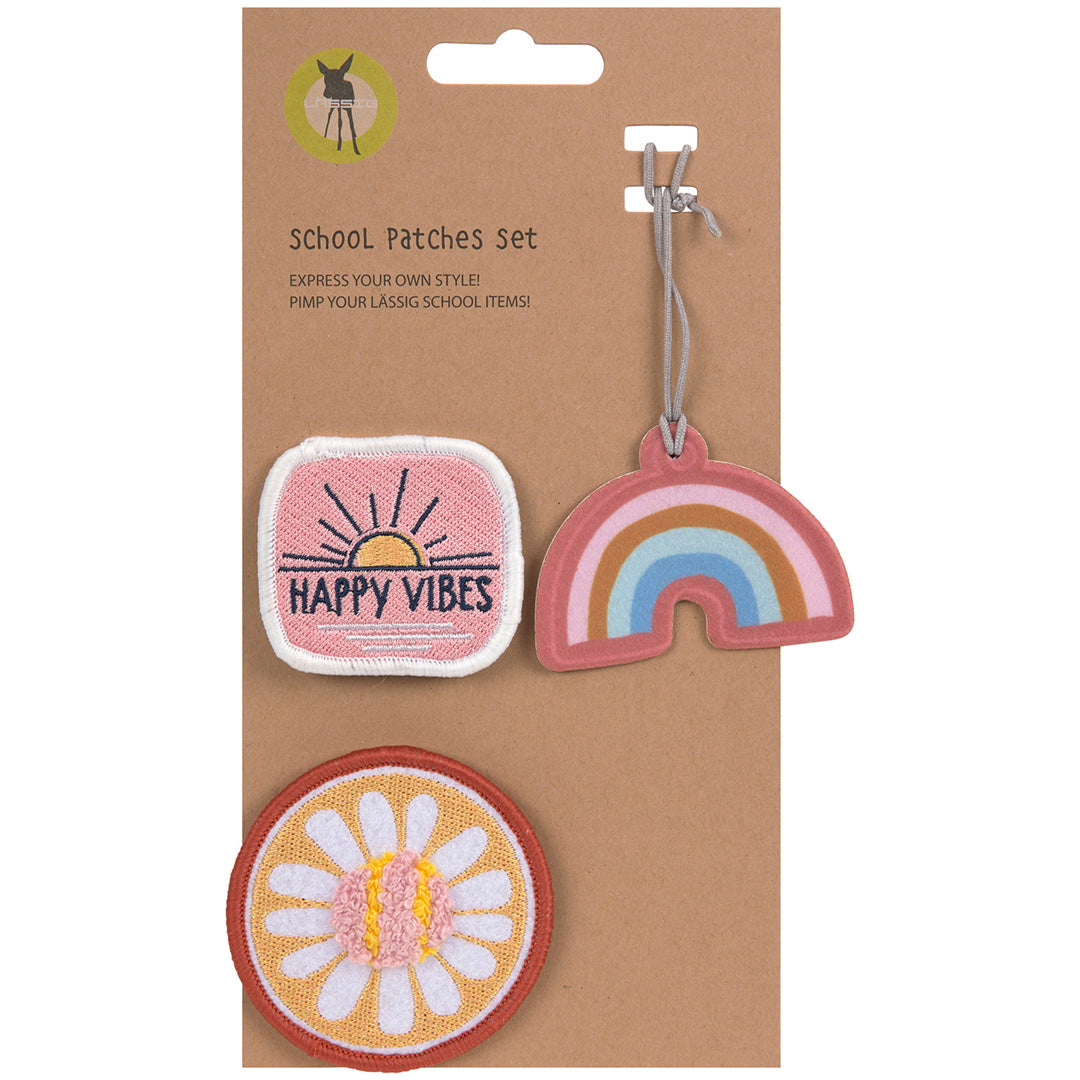 Lässig School Patches set verpakking met een vierkante patch met 'HAPPY VIBES', een ronde bloemenpatch en een regenboog hanger.