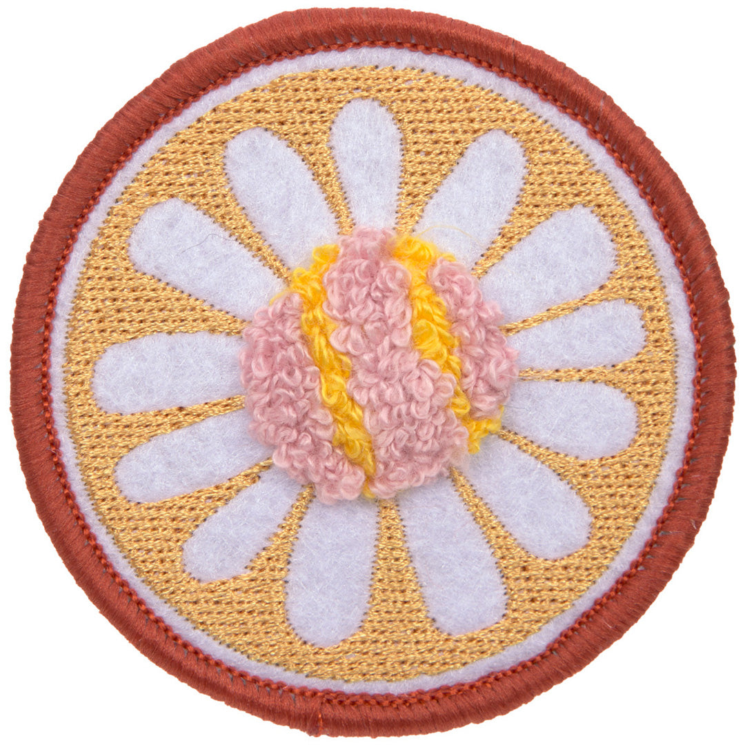 Detail van een ronde gebloemde patch met een witte bloem op een gele achtergrond.
