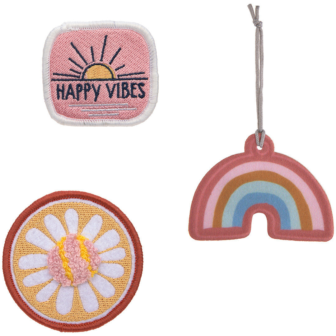 De drie Lässig patches samen: een vierkante patch met 'HAPPY VIBES', een ronde bloemenpatch en een regenboog hanger.
