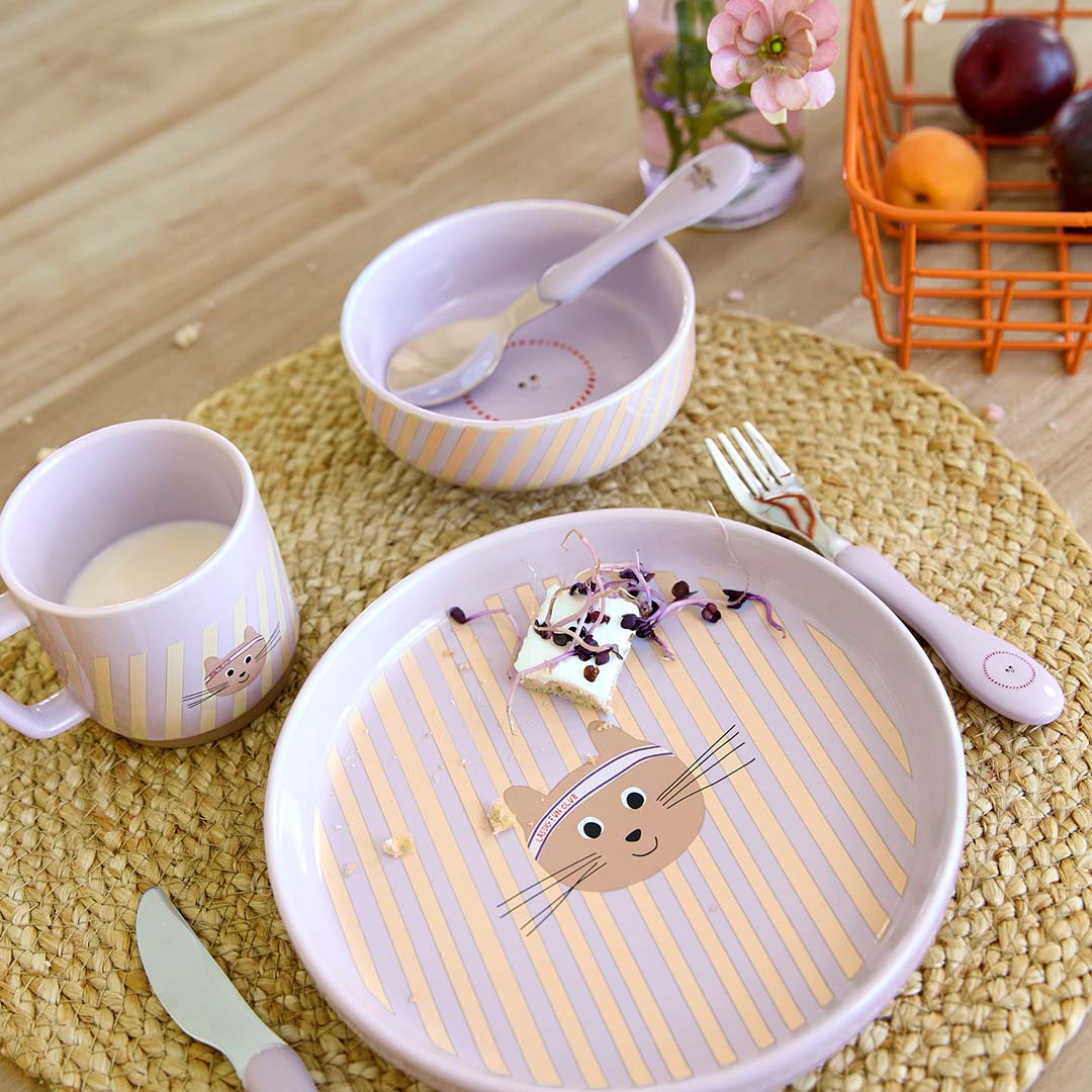 De Lässig kinder serviesset met kattengezicht en paarse strepen staat op een tafel met bestek en restjes eten.