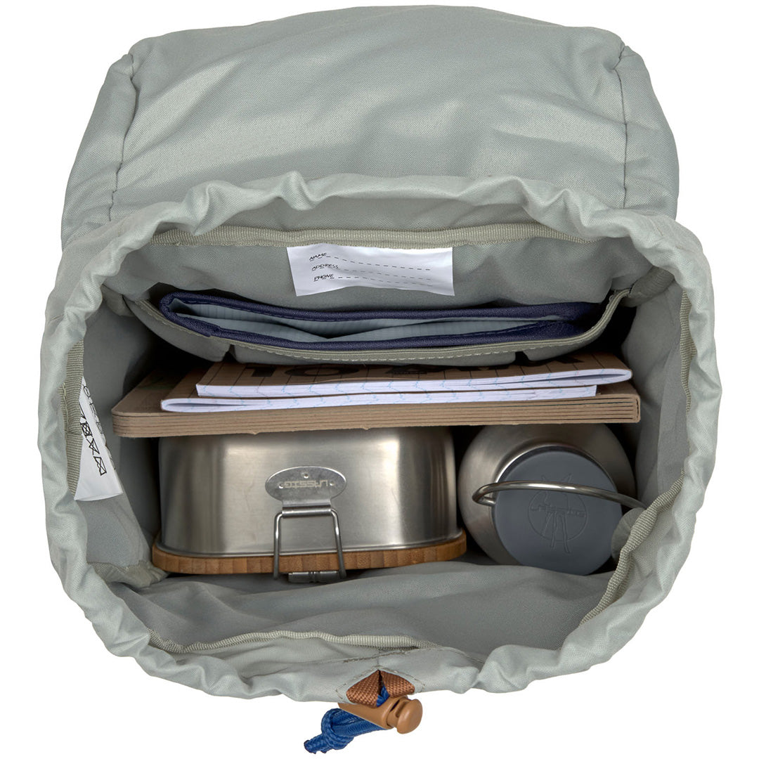 Binnenzijde van een open rugzak met een metalen lunchbox, waterfles en notitieboek.