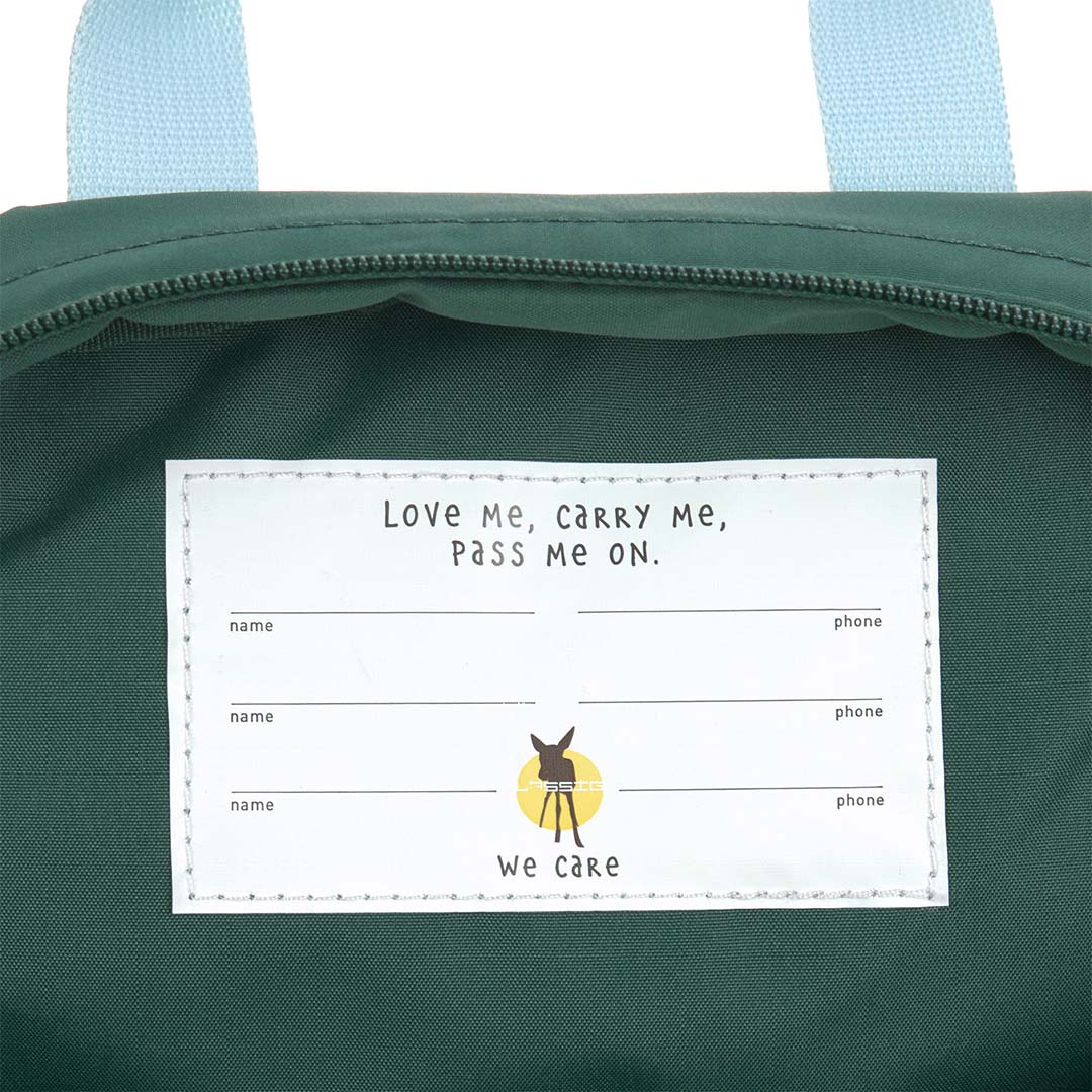 Detail van het interne label in de Lässig kleuterrugzak met de tekst "Love Me, Carry Me, Pass Me On".