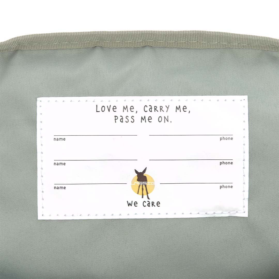 Detail van het interne label van de Lässig kleuterrugzak met de tekst 'Love Me, Carry Me, Pass Me On' en invulvelden.