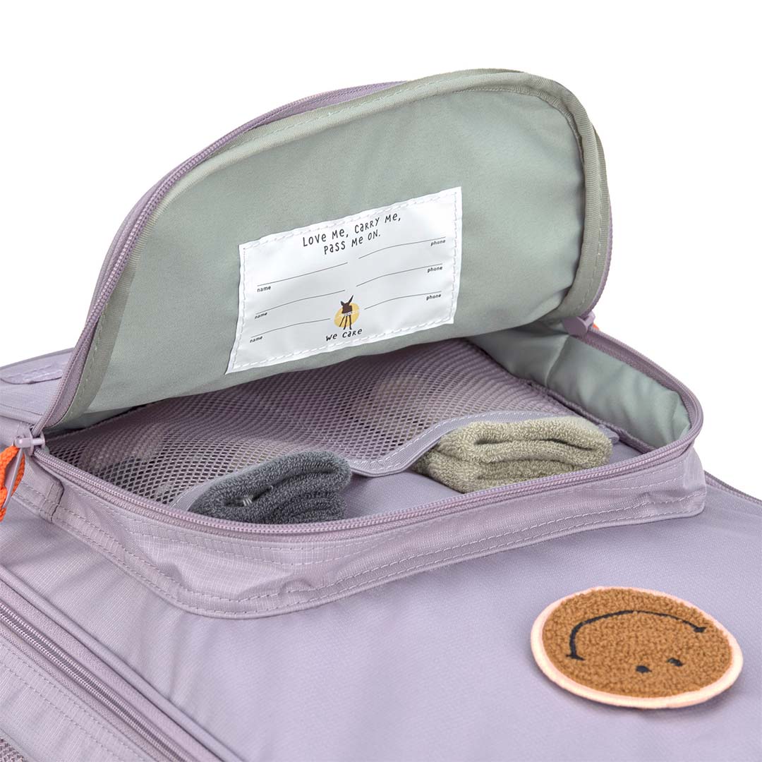 Detail van de open lässig kinderkoffer in lila met een naamlabel en interne opbergvakken.