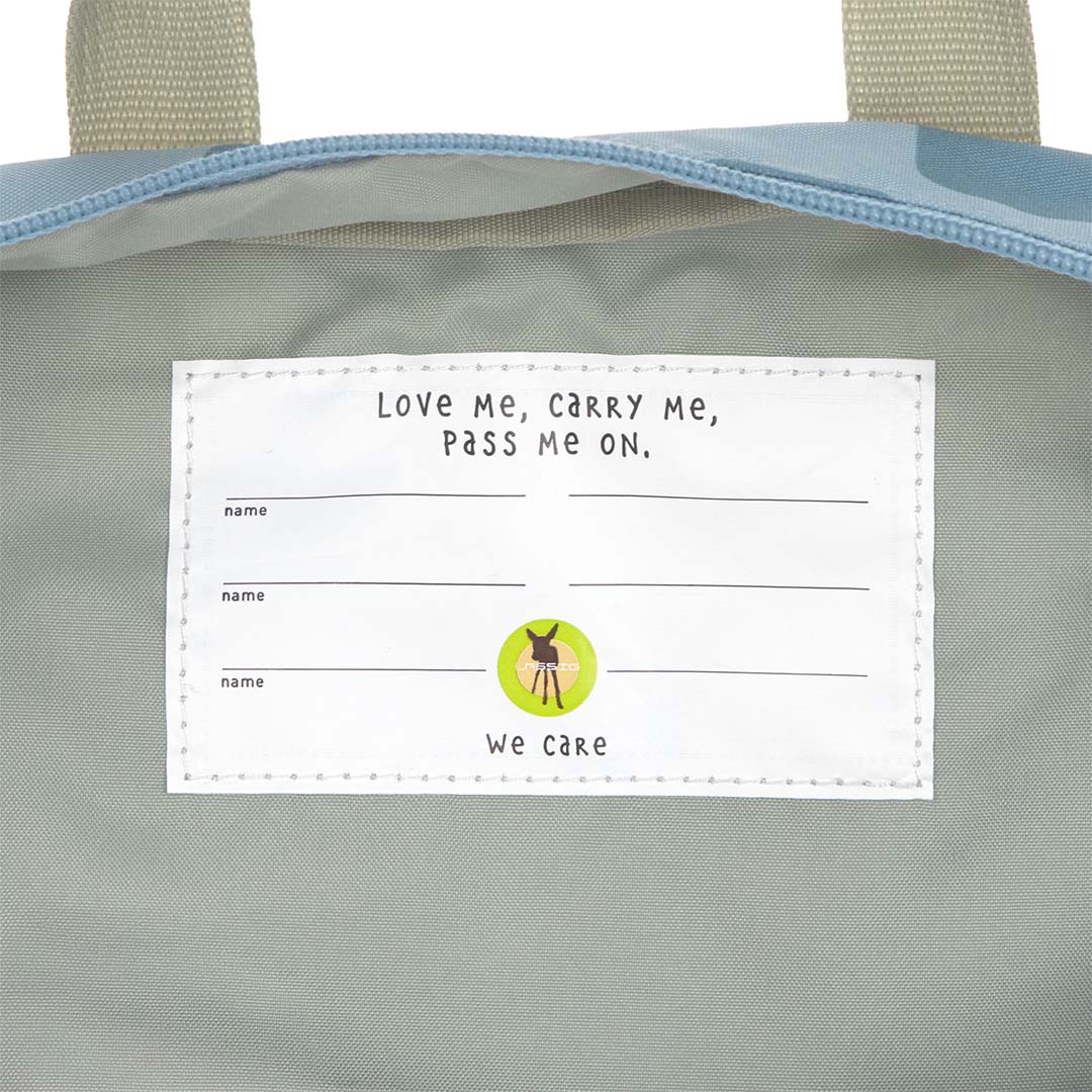 Detail van het interne naamlabel in de Lässig kleuterrugzak met de tekst "Love Me, Carry Me, Pass Me On".