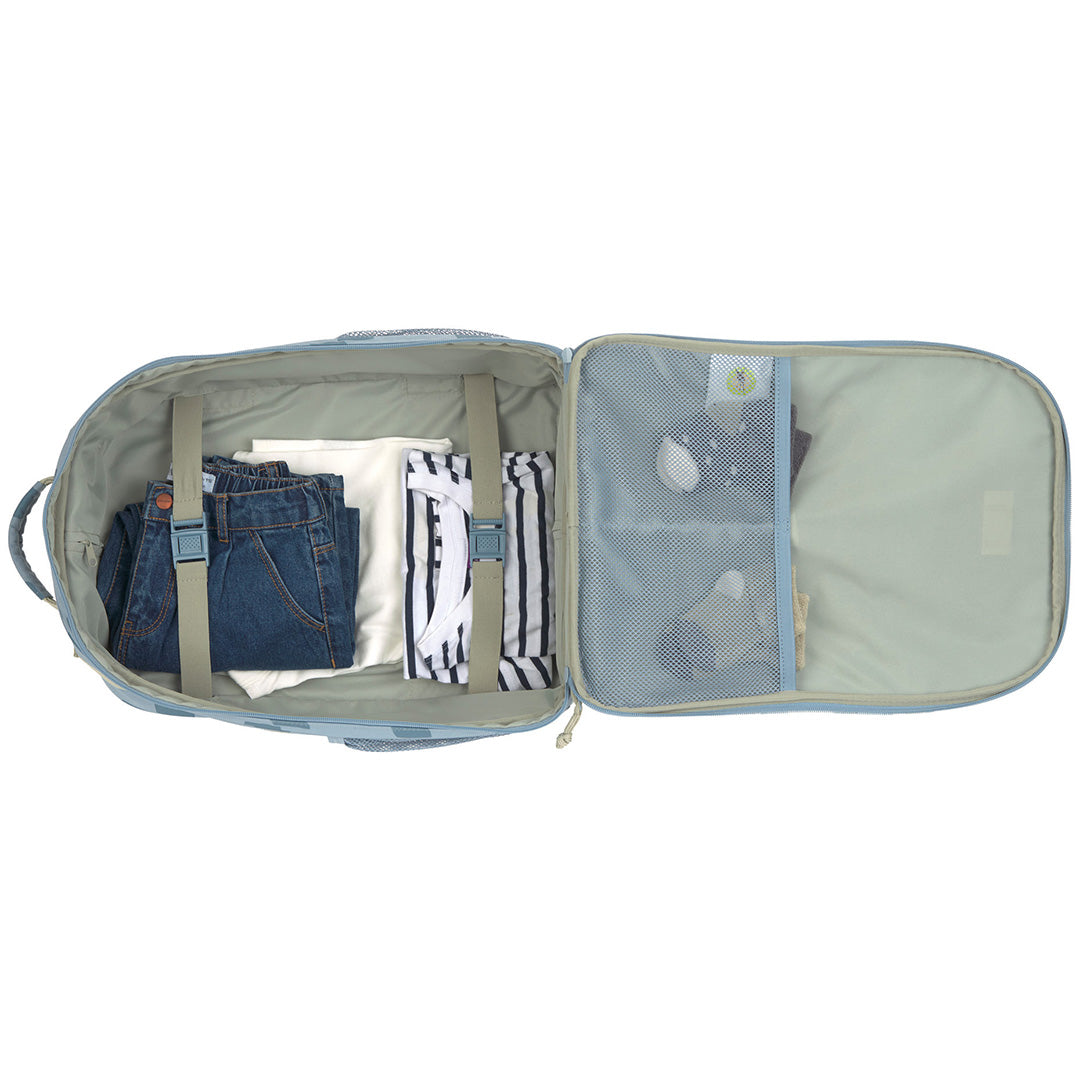 De open blauwe kinderkoffer met kleding en accessoires netjes opgeborgen in de vakken.