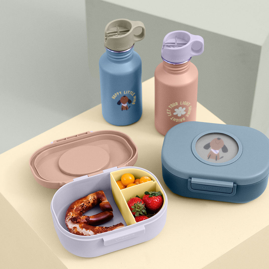 Twee Lässig kinder drinkflessen en twee open lunchboxen, waarvan één gevuld met eten, op een lichte achtergrond.