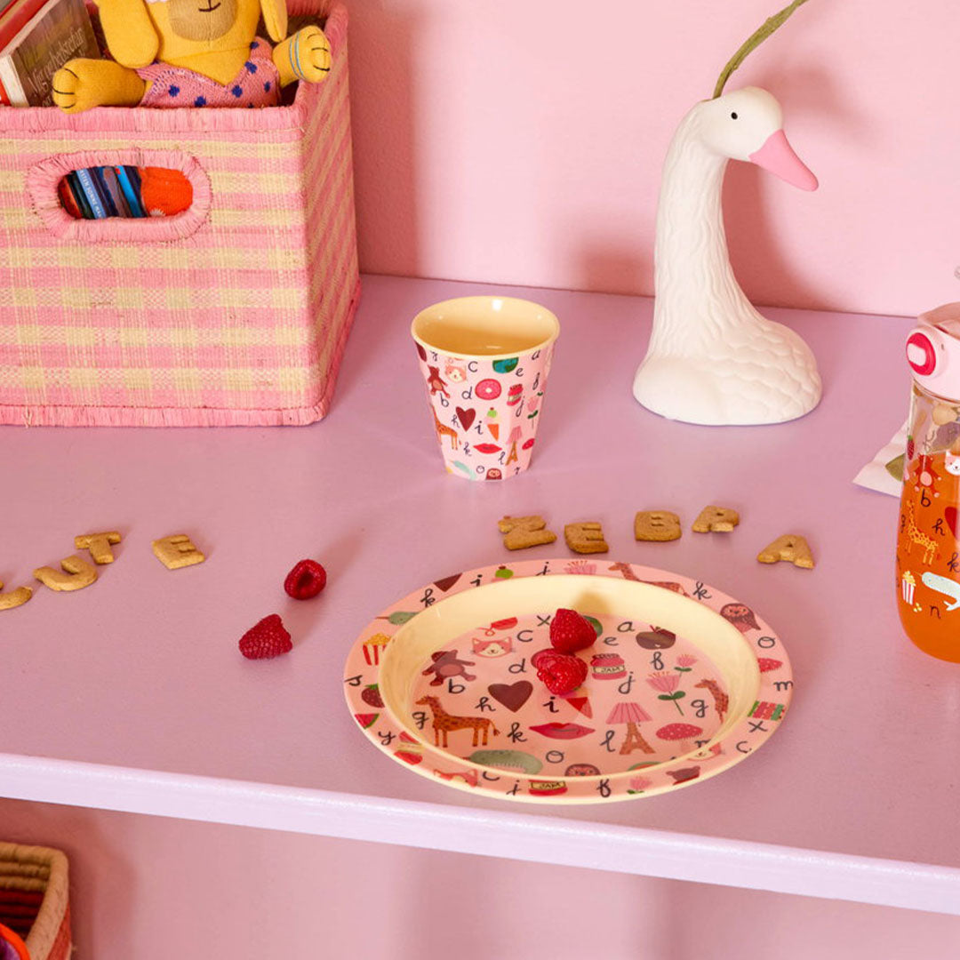 Kinderbord met ABC- en figurenpatroon op een roze plank met frambozen.