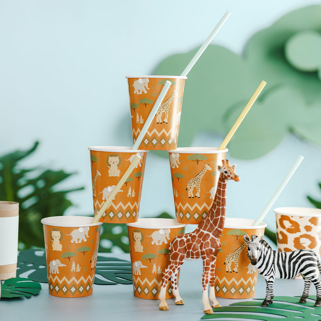 partydeco safari papieren feestbekers met rietjes, samen met speelgoedgiraf en zebra op een feestelijke achtergrond.