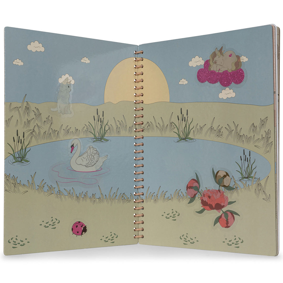 Een open stickerboek toont een landschap met een vijver, zwaan, lieveheersbeestje en eenhoornsticker.