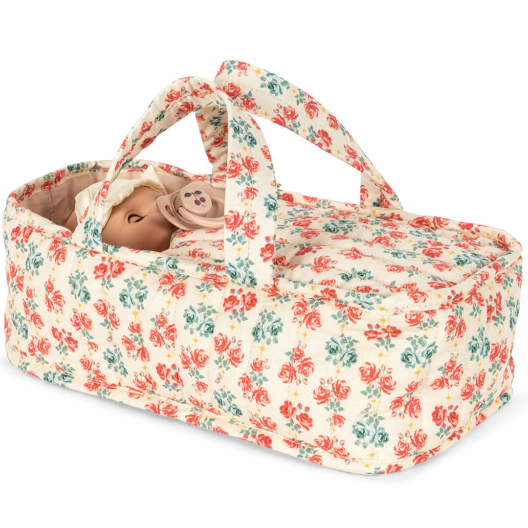 Konges Sløjd babypop met speen in een gebloemde reiswieg.